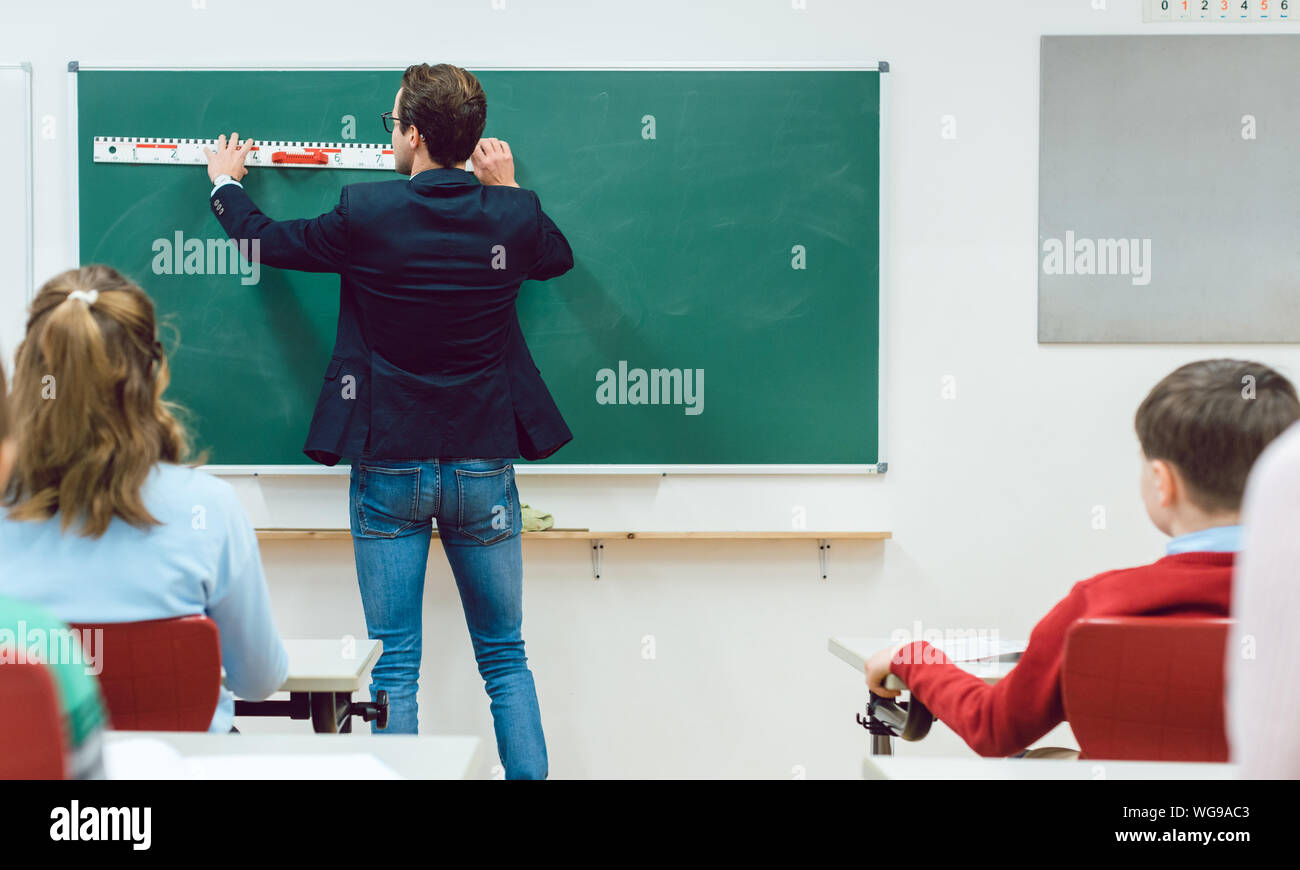 Students watching teacher drawing at the blackboard in classroom Stock Photo