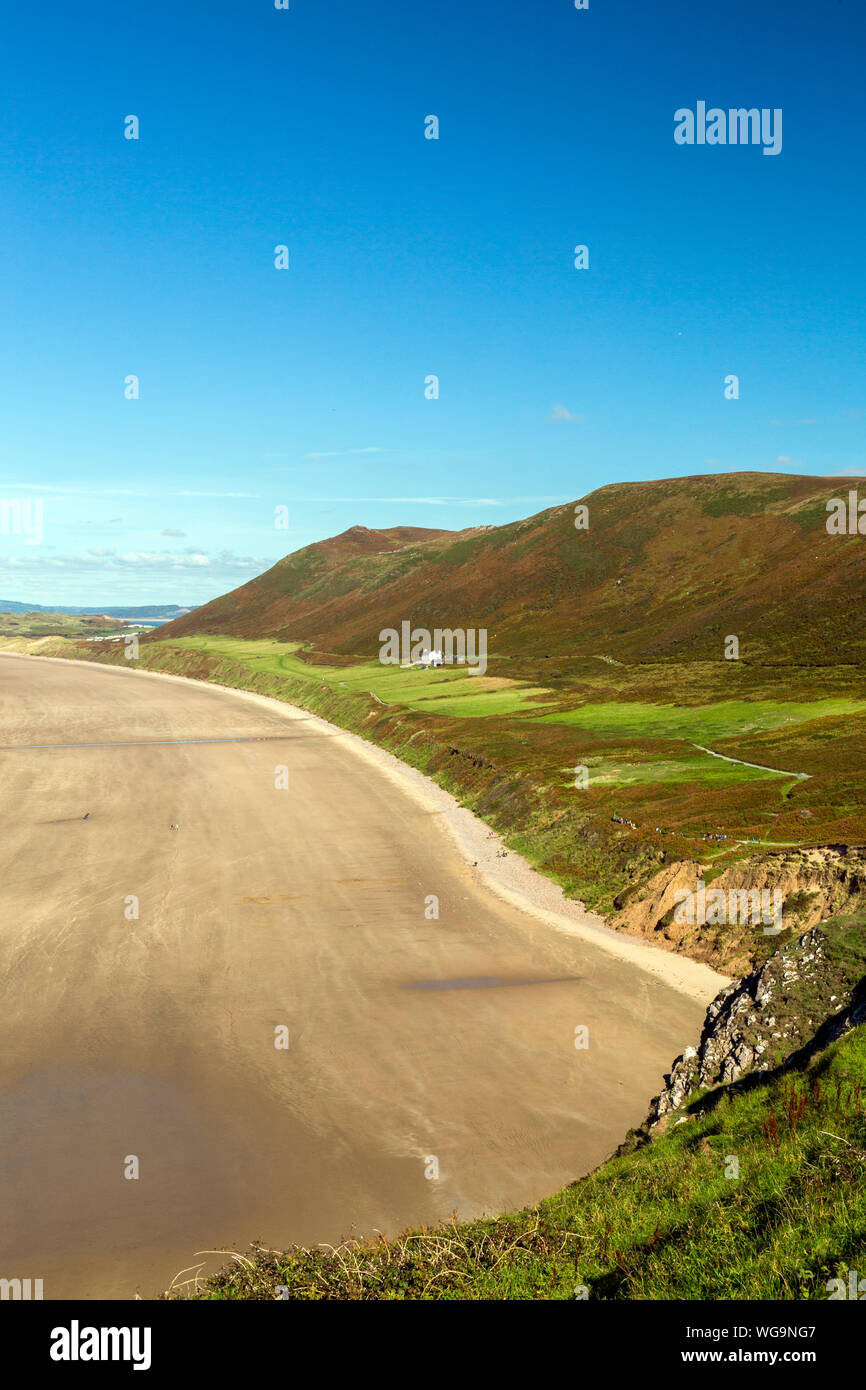 The extensive sandy beach in Rhossili Bay is overlooked by the ridge of Rhossili Down on the Gower peninsula, South Wales, UK Stock Photo