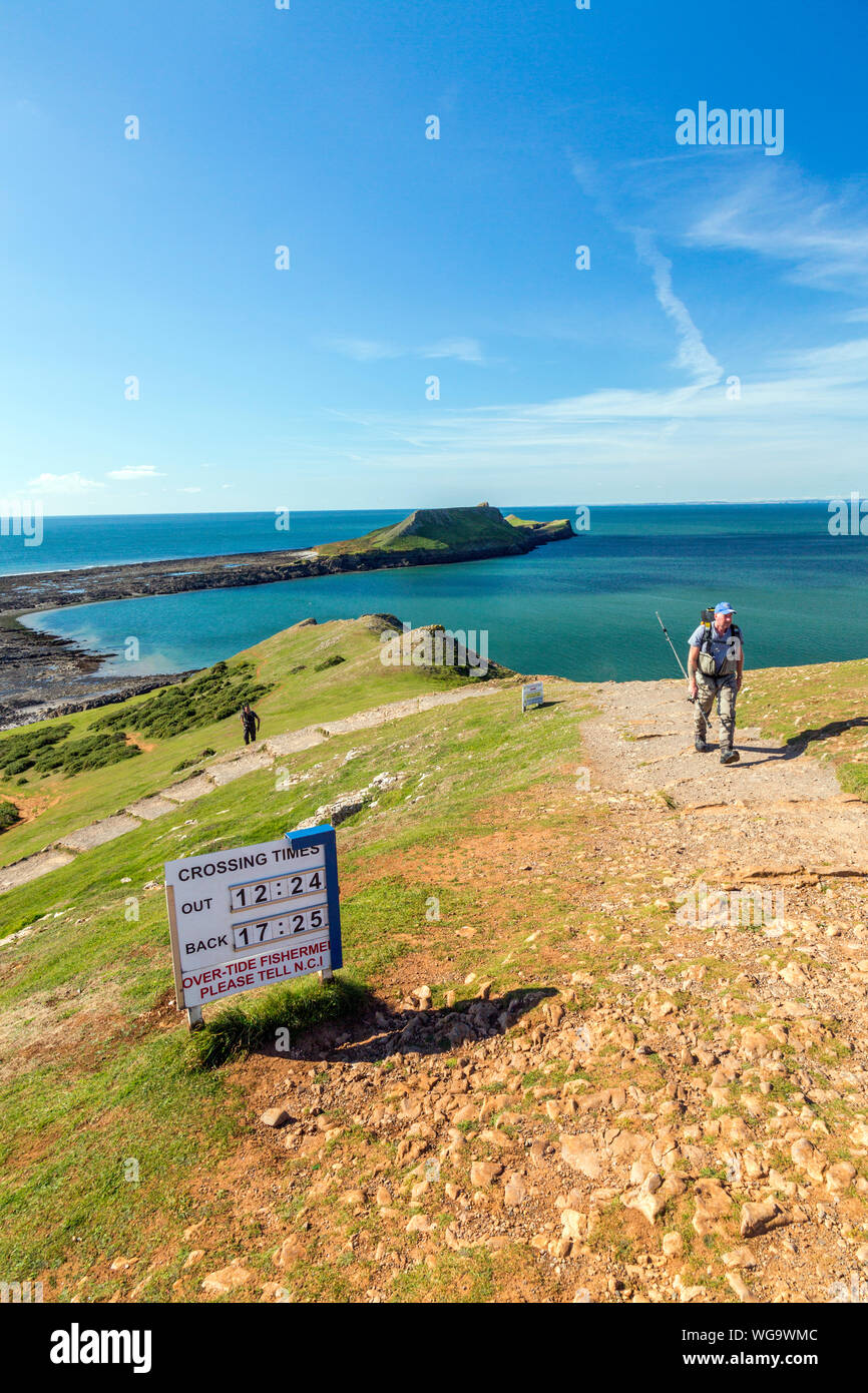 Warning sign giving tide times when it's possible to cross to Worms Head on the Gower peninsula, South Wales, UK Stock Photo