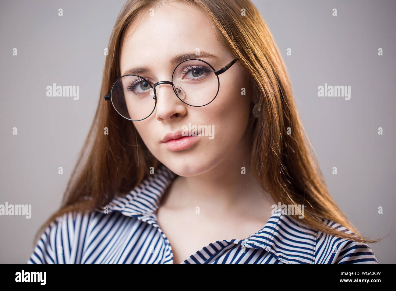Beautiful closeup portrait of a young student girl wearing glasses on a  gray background. Attractive redhead woman with natural beauty looks at the  cam Stock Photo - Alamy