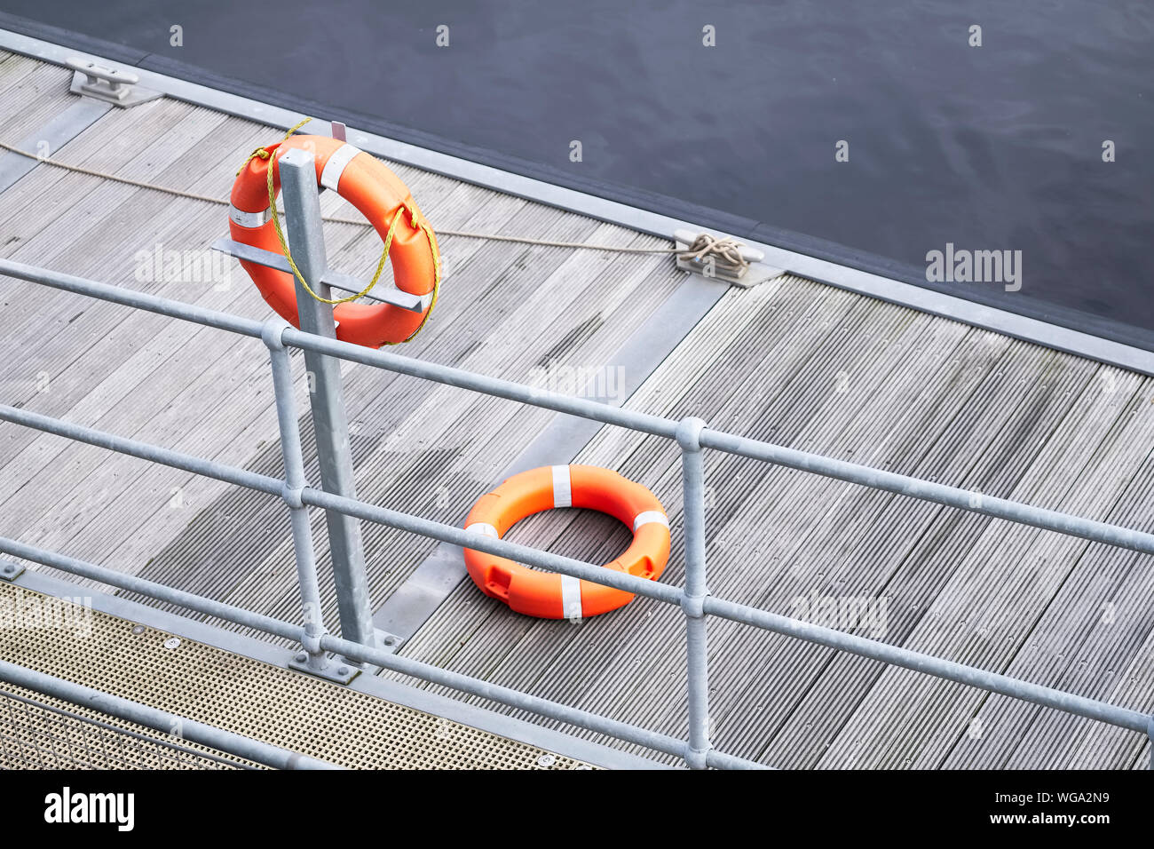 Lifebuoy orange ring on sea pontoon for water safety at marina Stock Photo