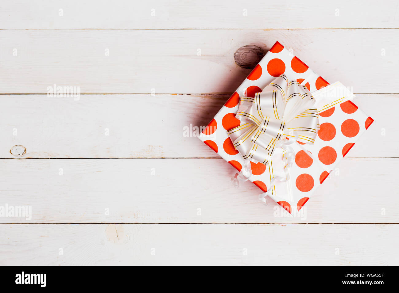 Red gift box with ribbon on white wooden background with copy space ...