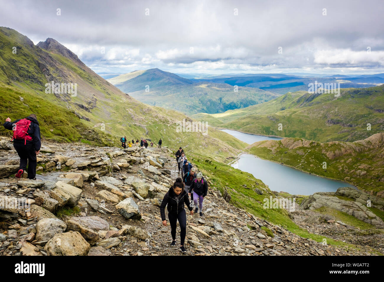 People walking up worn eroded Pyg Track busy route to Mt Snowdon above Glaslyn in mountains of Snowdonia National Park. Llanberis Gwynedd Wales UK Stock Photo