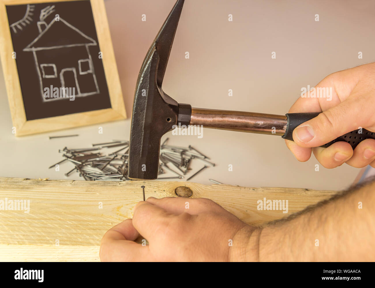 Cropped Image Of Carpenter Hammering Nail On Wood Stock Photo