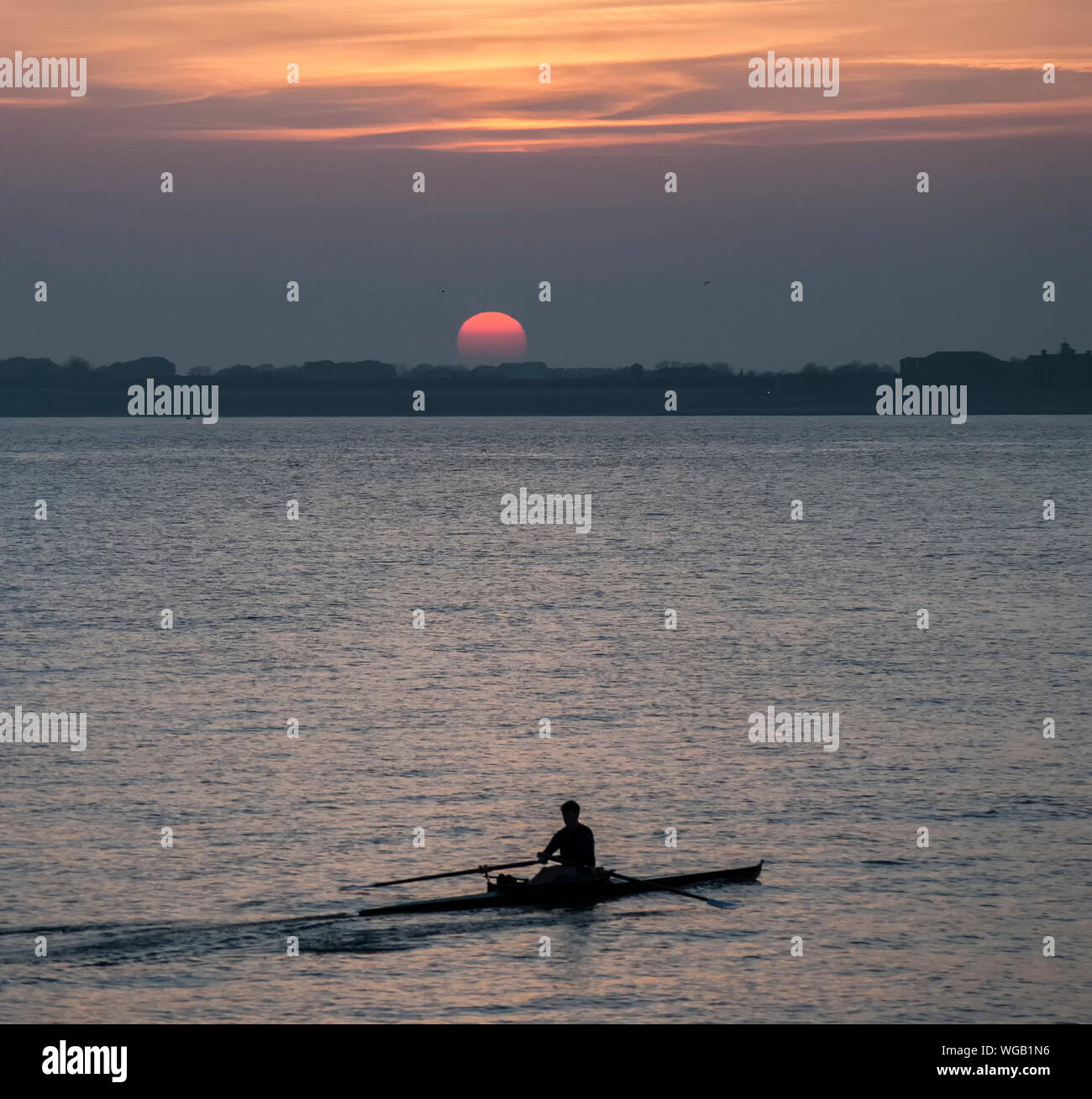 Silhouette Man Rowing Boat On Lake Against Sky During Sunset Stock Photo