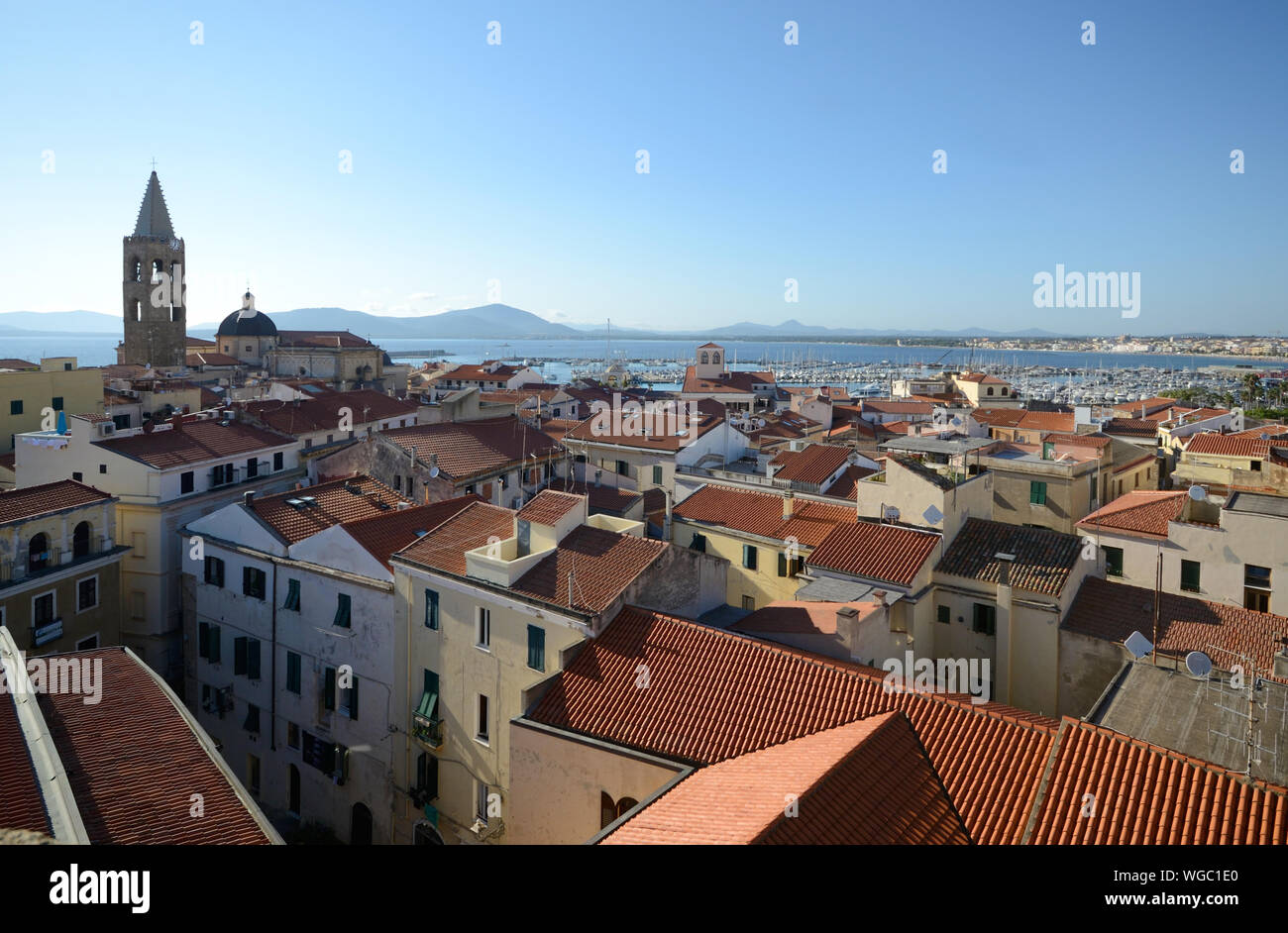 Aerial view of Alghero, city of Sardinia, with the bell tower of the cathedral in evidence and the sea and the hills in the background Stock Photo