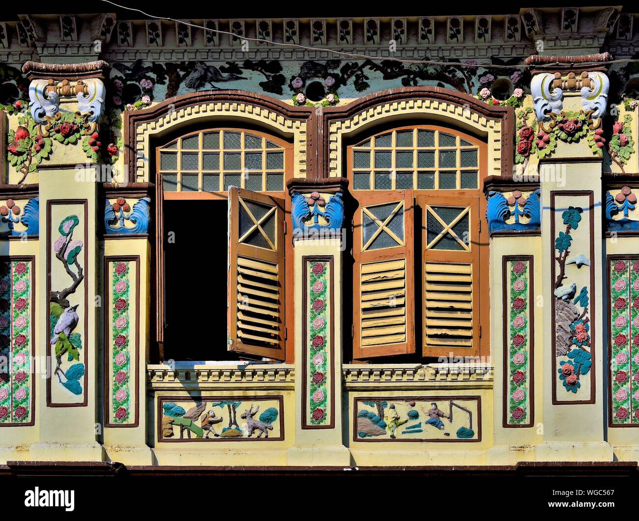 Front view of traditional Peranakan Straits Chinese shophouse exterior with antique wooden shutters and ornate carvings in Geylang, Singapore Stock Photo