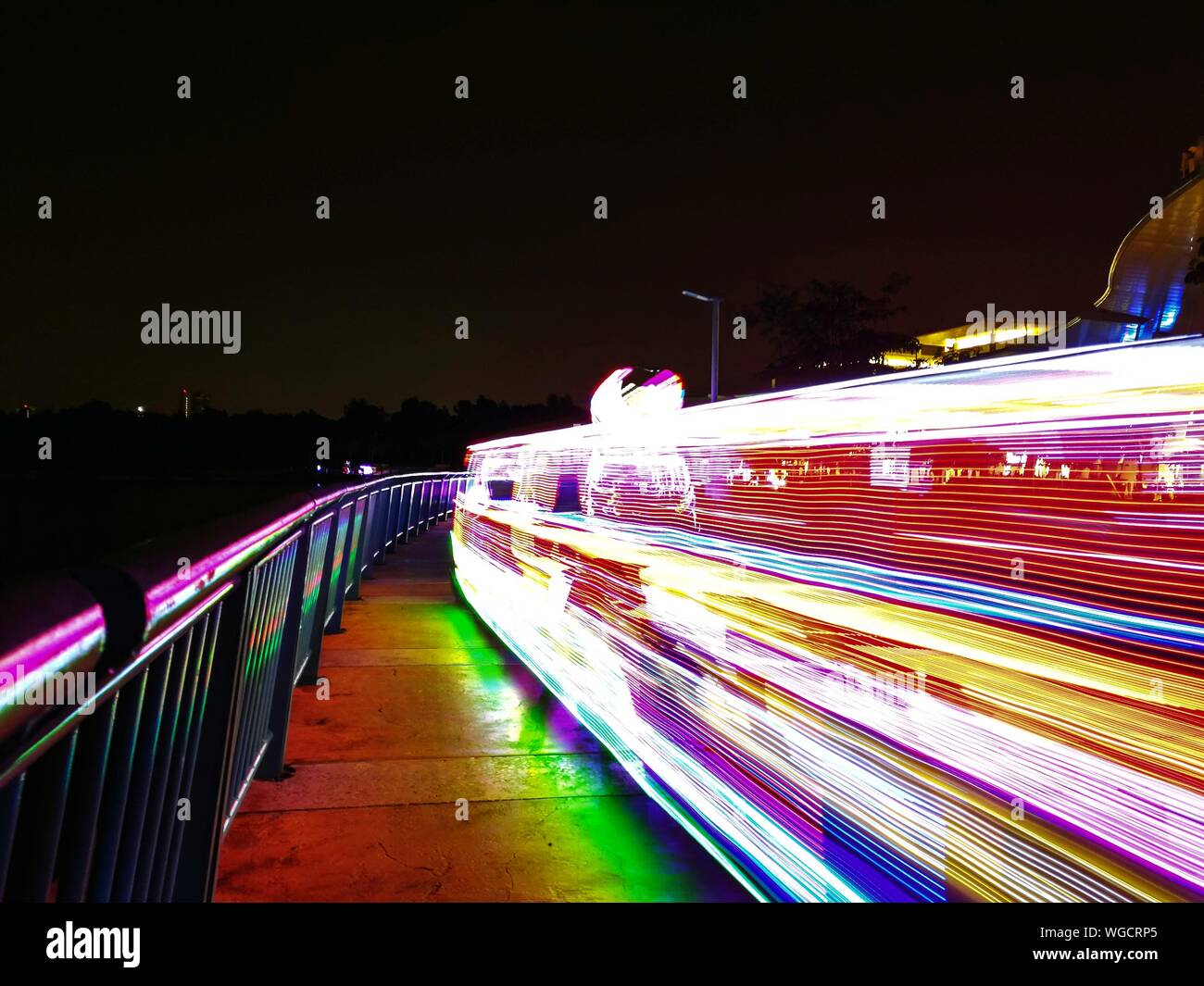 Light Trails On Illuminated City Against Sky At Night Stock Photo
