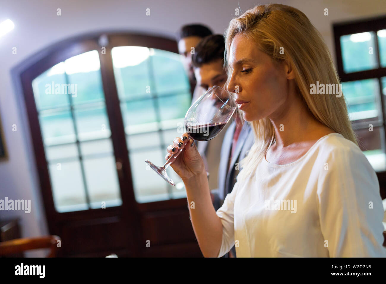 Beautiful blonde woman drinking glass of red wine Stock Photo - Alamy