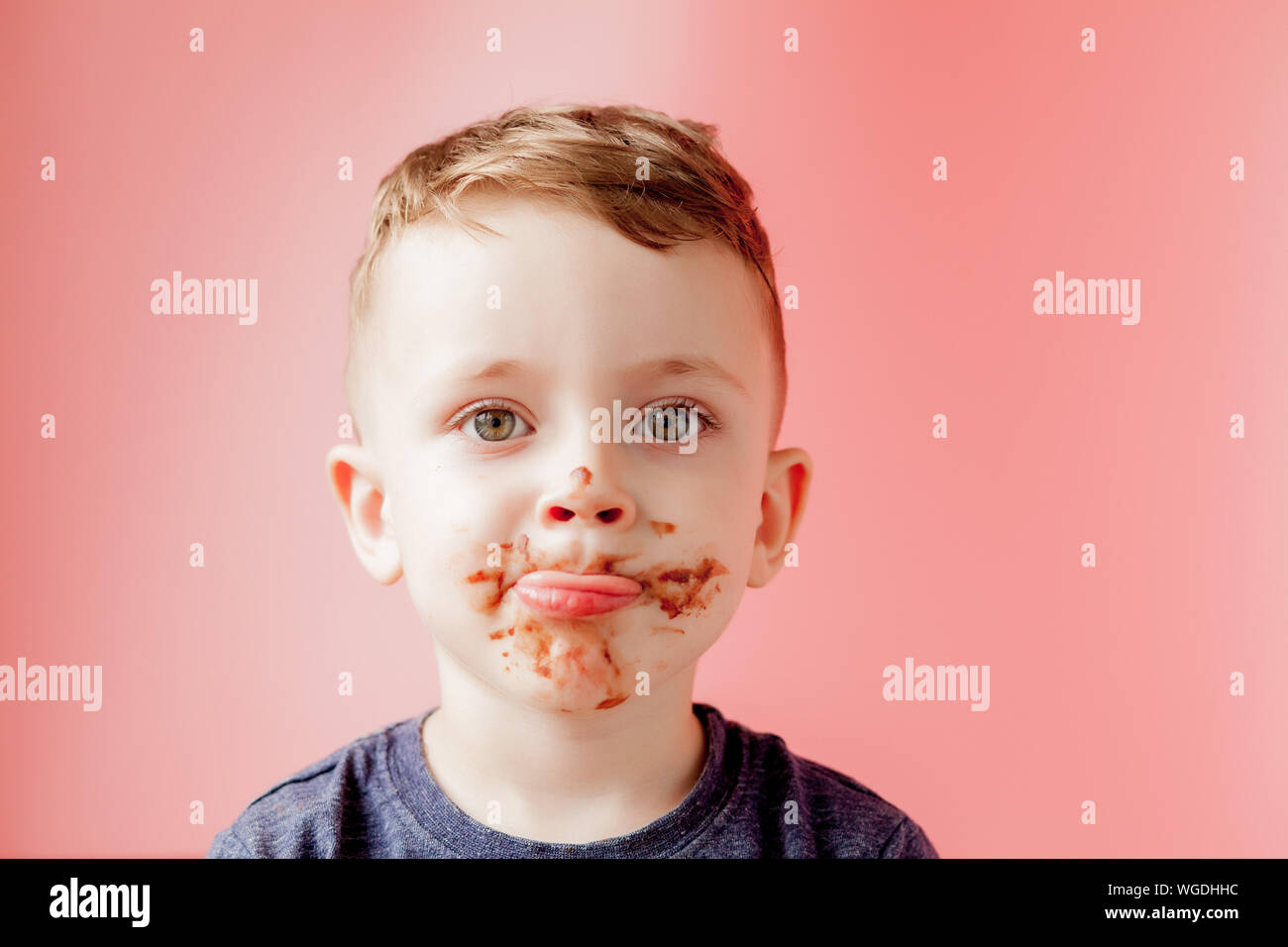 Little boy eating chocolate. Cute happy boy smeared with chocolate