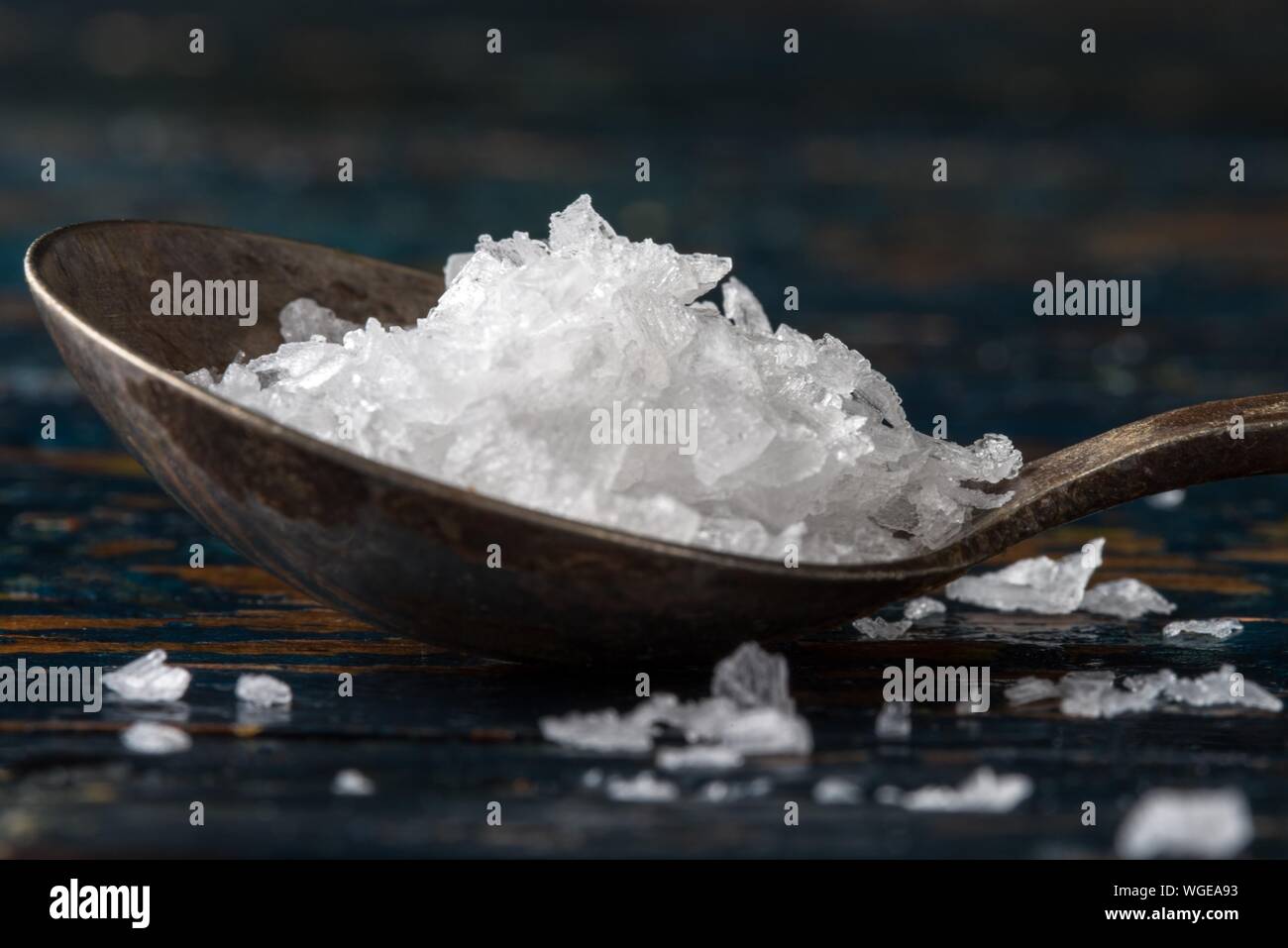Close-up Of Flake Salt In Spoon On Wooden Table Stock Photo
