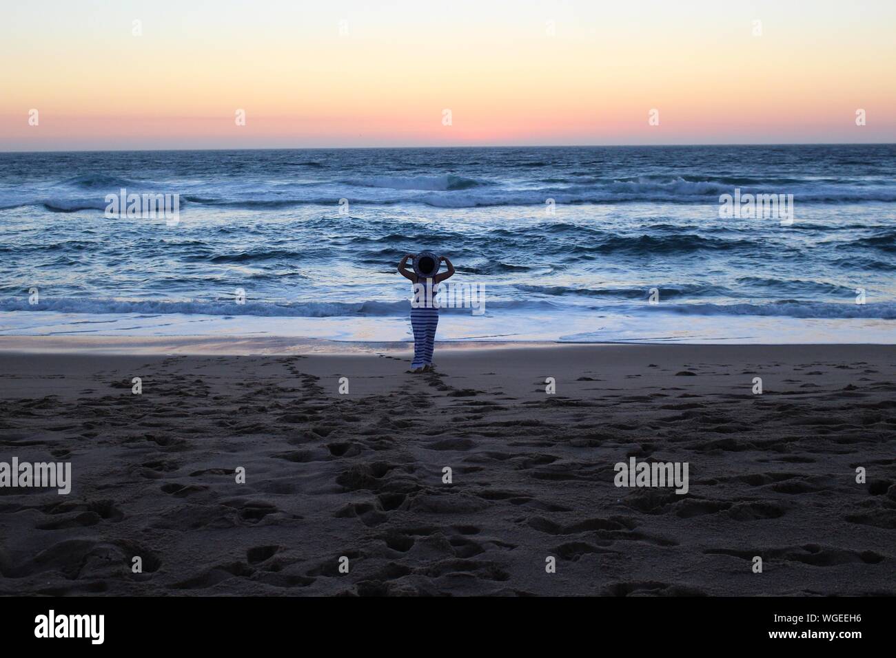 Woman Hiding Face From Hat At Beach Against Sky During Sunset Stock Photo Alamy