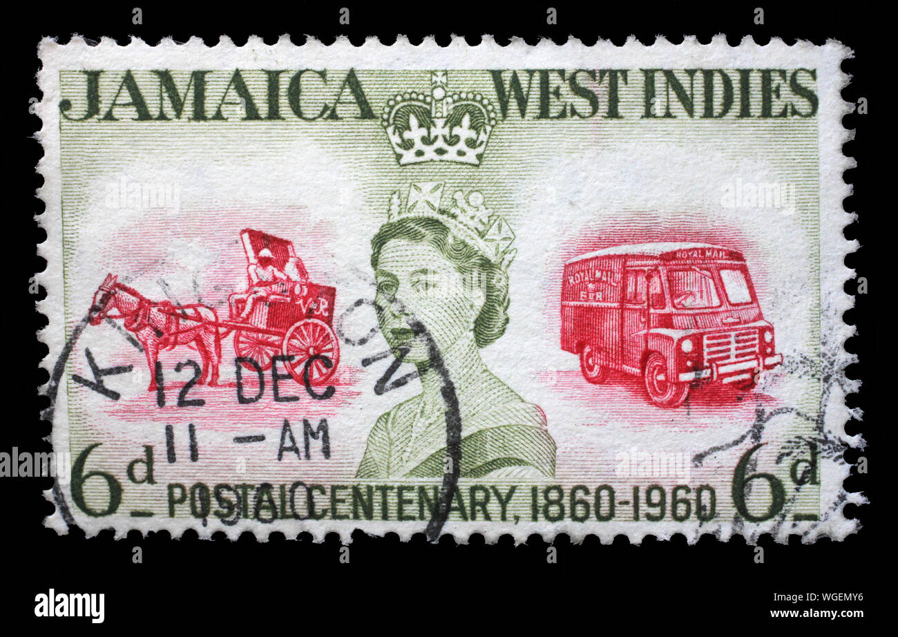 Stamp printed in Jamaica shows and Queen Elizabeth II and coach and bus, the 100th Anniversary of Jamaican Postal Service, circa 1960. Stock Photo