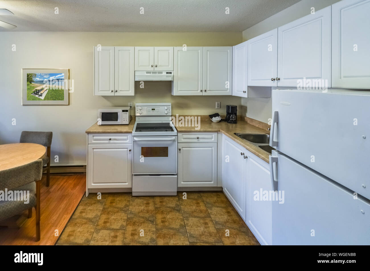 Regular white kitchen with the table and chairs in dinner area Stock