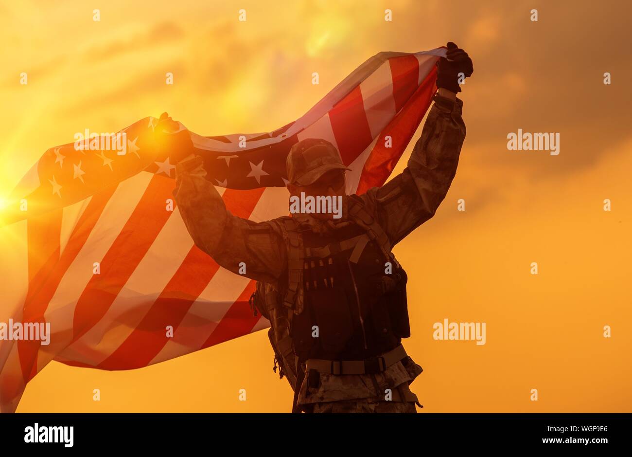 Mid Adult Man Holding American Flag Against Sky During Sunset Stock Photo