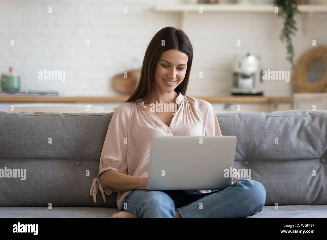 Woman looking at computer screen resting on couch at home Stock Photo