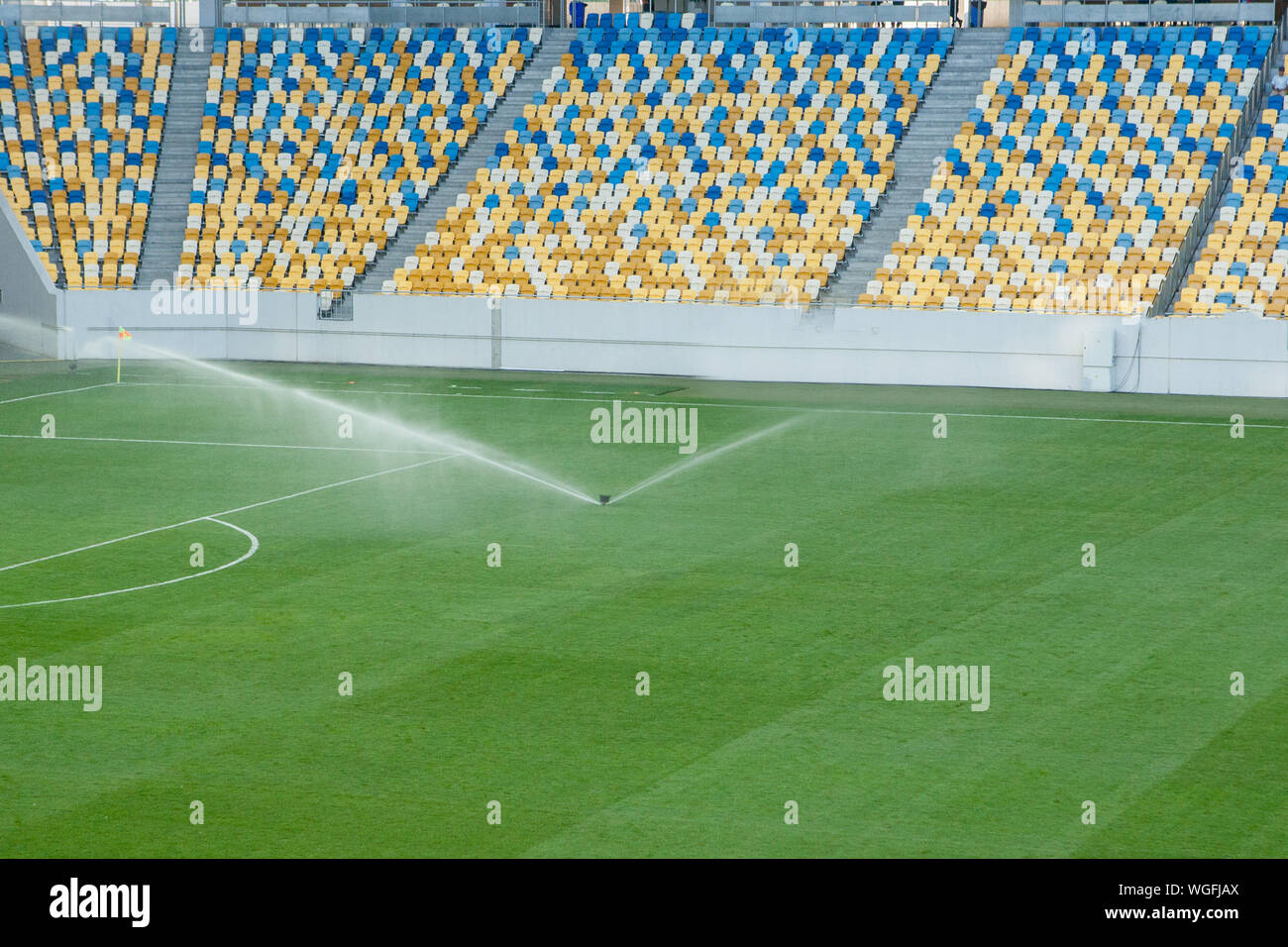 Automatic lawn grass watering system at the stadium. A football, soccer field in a small provincial town. Underground sprinklers spray jets water. Stock Photo