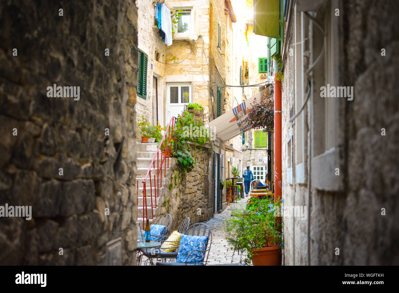 A shady, narrow alley off the beaten path in the old town residential section of Split Croatia with a man jogging. Stock Photo