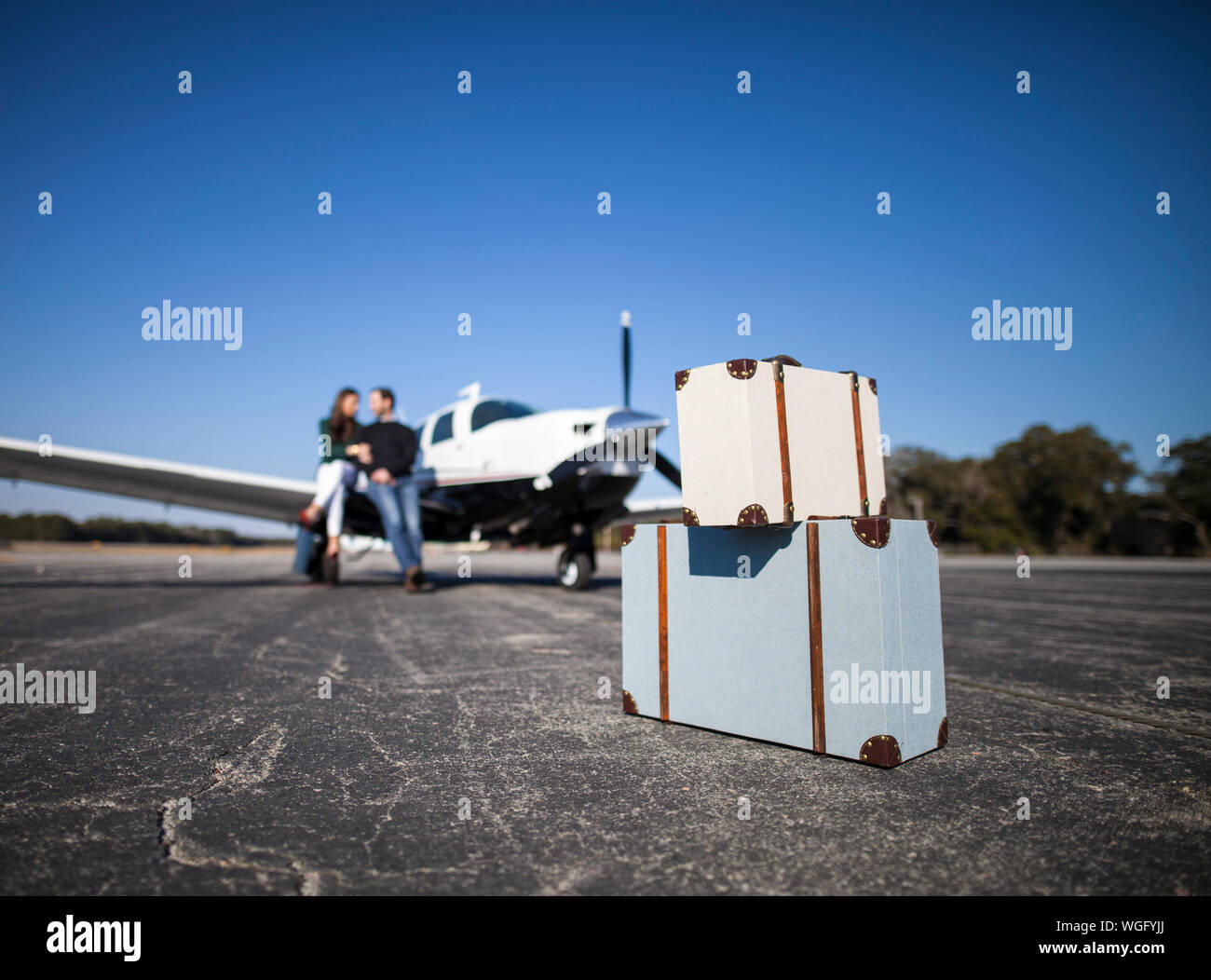 Couple getting ready to go on private plane, focus on bags in foreground Stock Photo