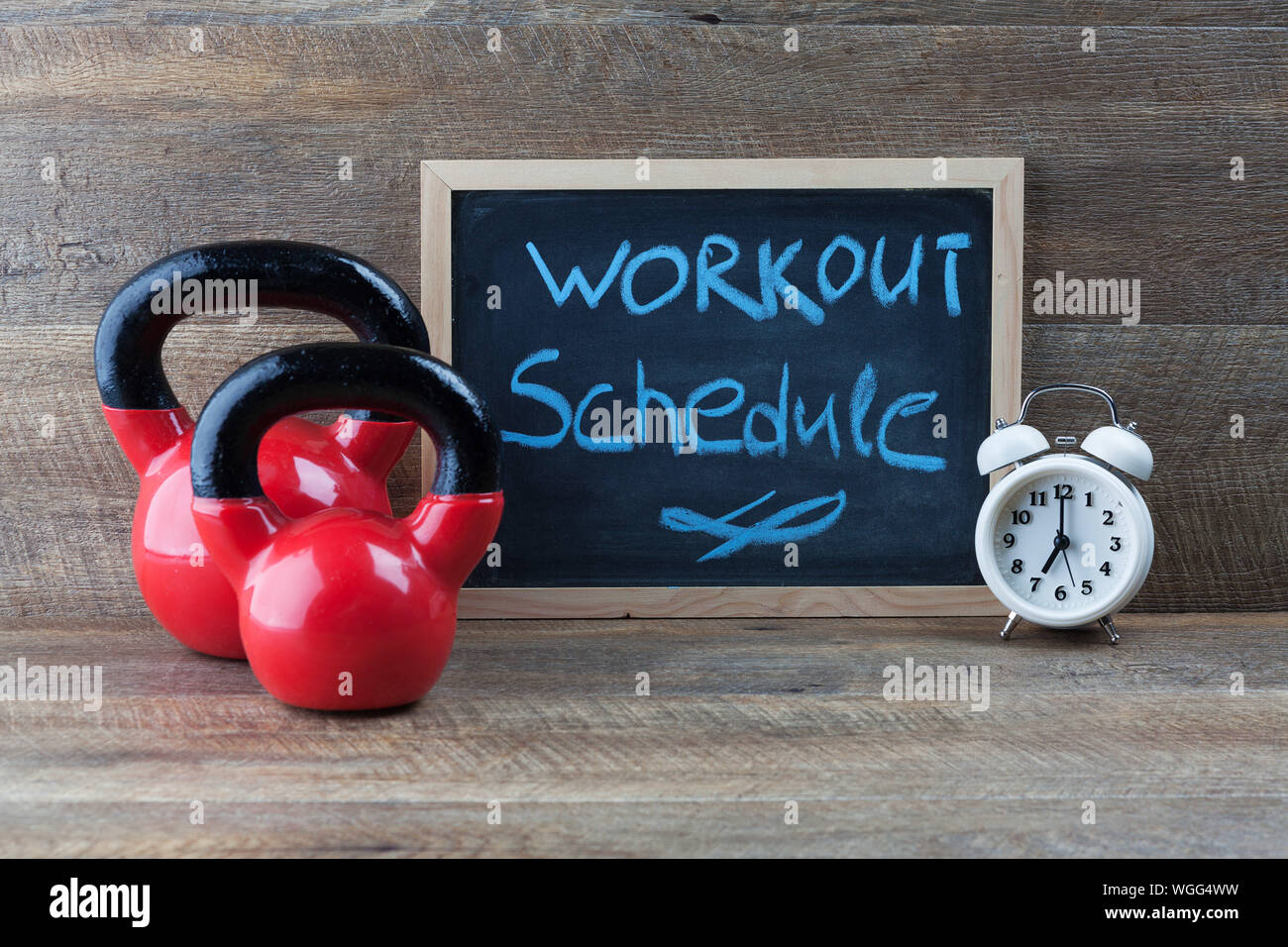 Close-up Of Alarm Clock With Kettlebells And Writing Slate On Table Stock Photo