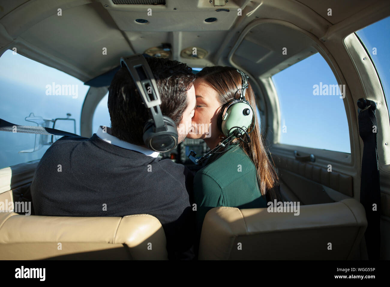 Young jet setting couple kiss in private plane Stock Photo