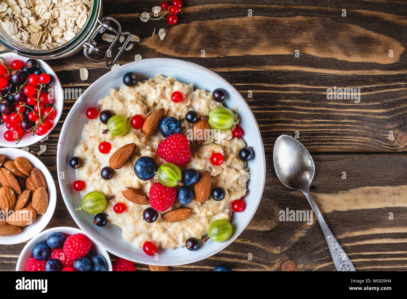 oatmeal porridge with fresh berries and nuts in a bowl on rustic wooden background for healthy diet breakfast. top view with copy space Stock Photo