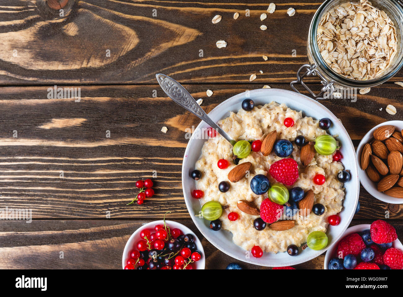 healthy breakfast. bowl of oatmeal porridge with berries, nuts and spoon on rustic wooden table. top view with copy space Stock Photo