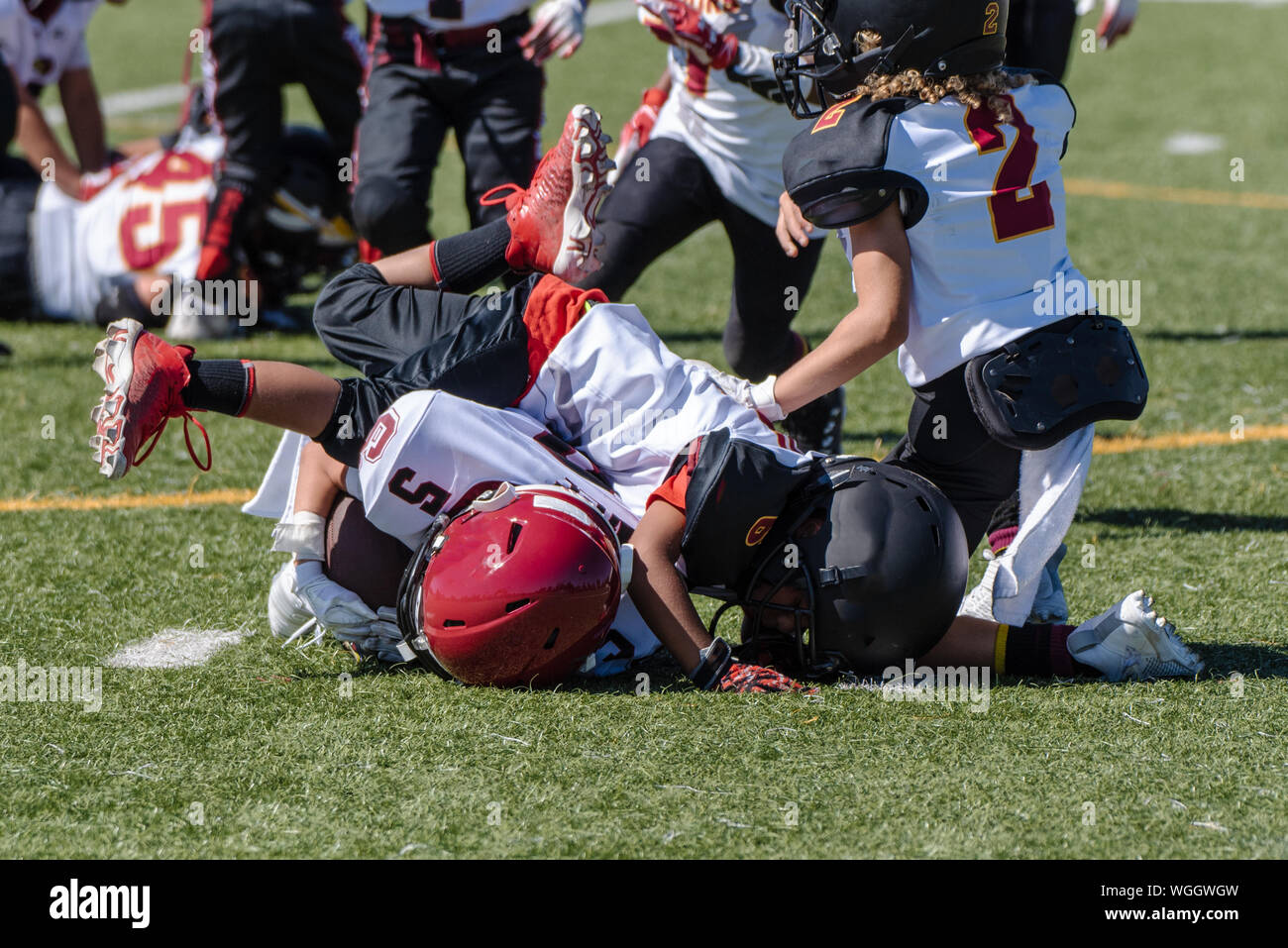 Offensive youth football player is tackled and at bottom of pile during