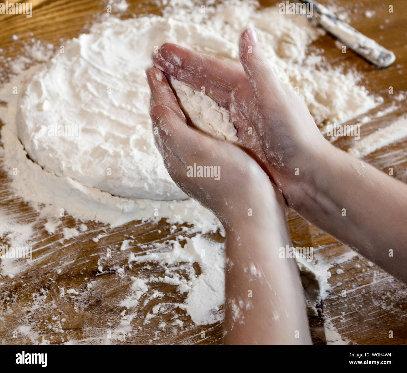 Cropped Hands On Kid Flattening Dough On Table Stock Photo