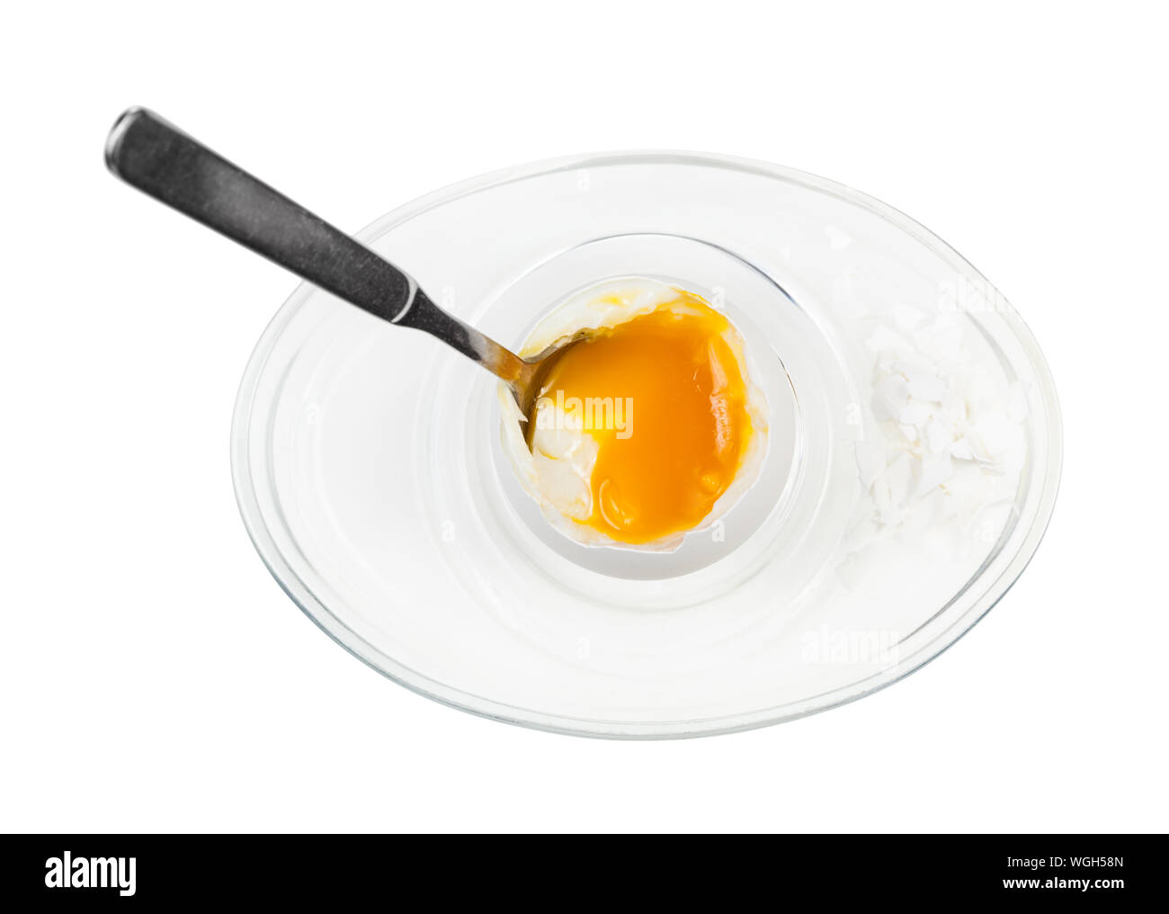 top view of open soft-boiled white egg with spoon in glass egg cup ...