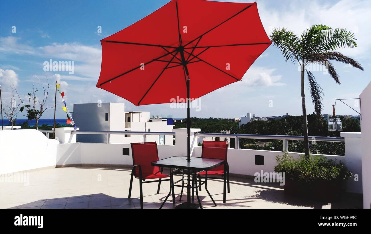 Chairs And Table Under Red Parasol At Restaurant Against Sky Stock Photo -  Alamy