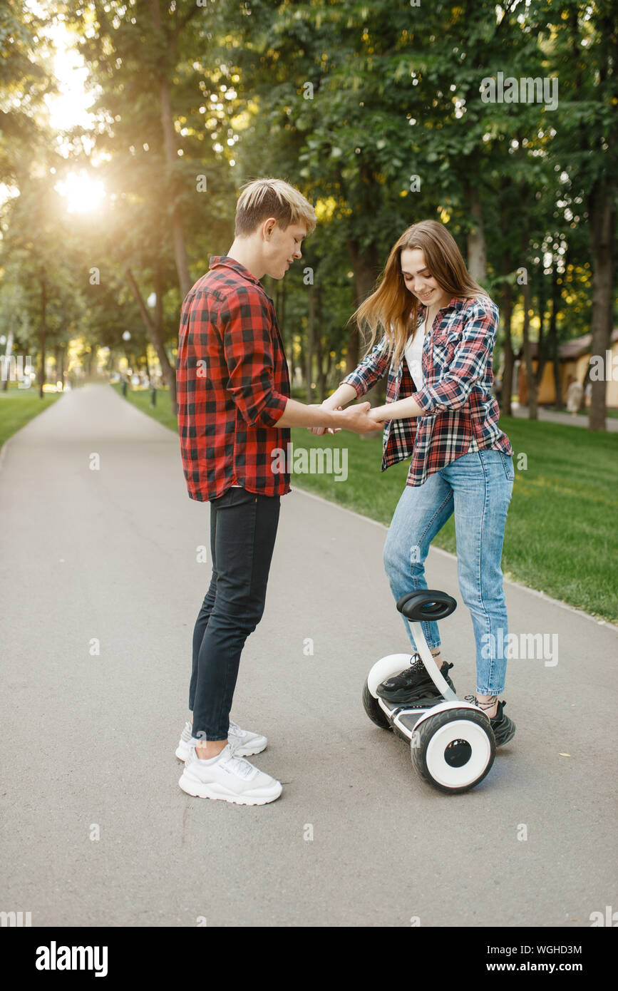 Boyfriend teaches his girl to ride on gyro board Stock Photo
