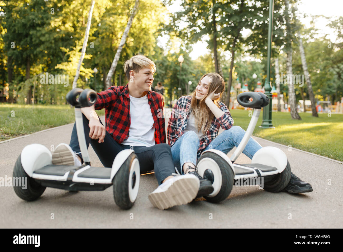 Young couple sitting on road with gyro board Stock Photo