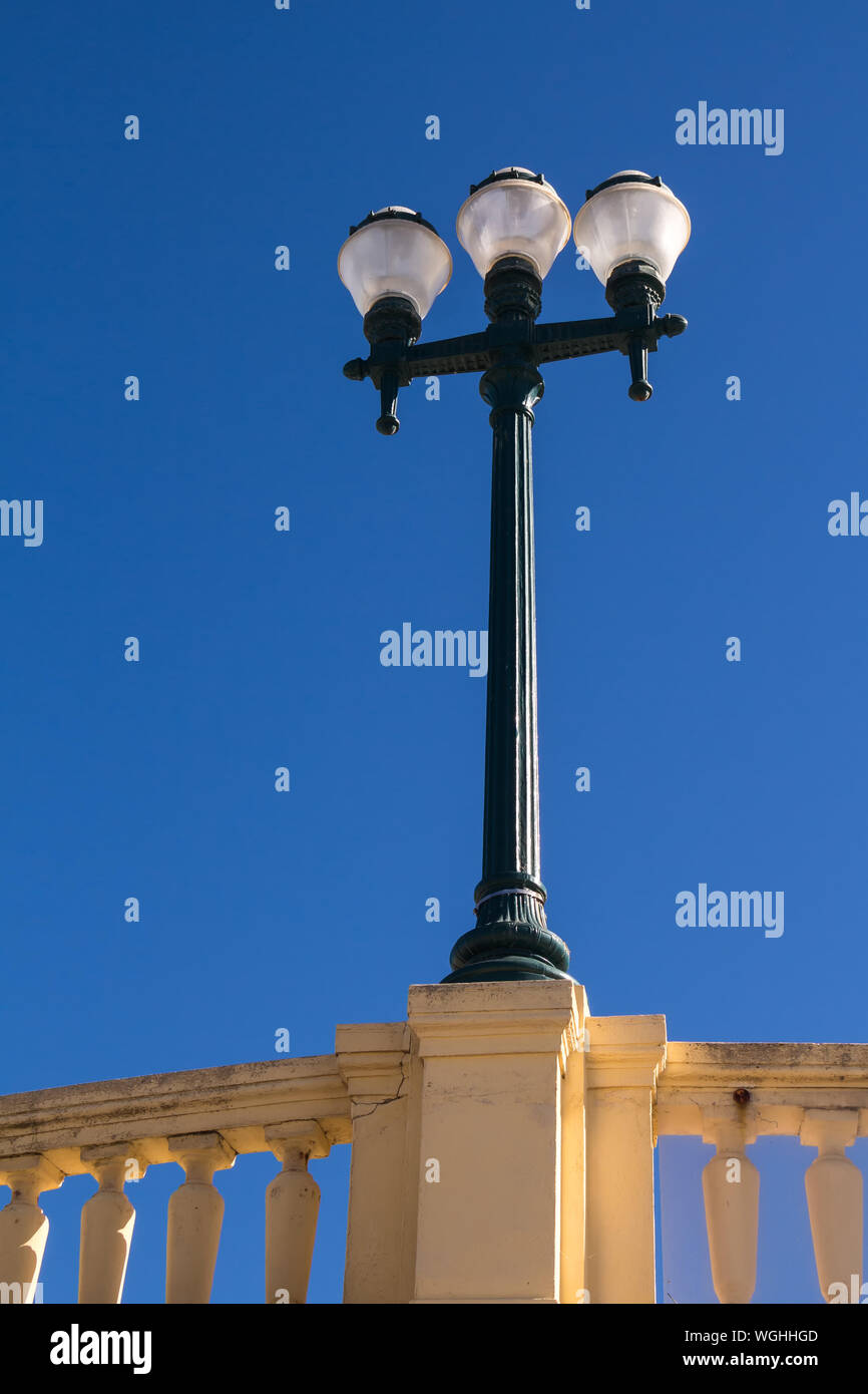 Streetlamp with three lights, standing on the fence of the promenade along the Atlantic ocean. Bright blue sky. Porto, Portugal. Stock Photo