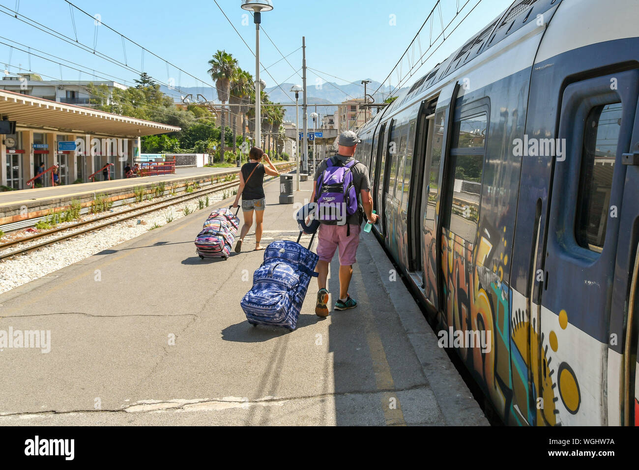 SORRENTO, ITALY - AUGUST 2019: People pulling suitcases along the platform to catch a train at Sorrento railway station. Stock Photo