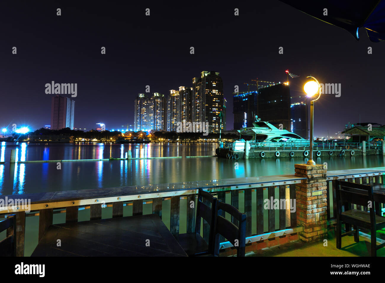 Restaurant By Saigon River With Illuminated City Buildings Seen In Background Stock Photo