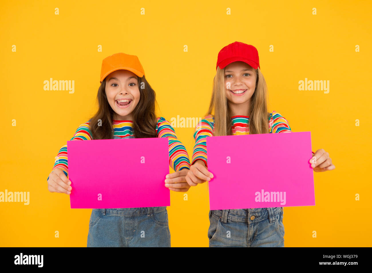 For your product. Happy children holding empty sheets of paper. Little children smiling with pink drawing paper. Small children with blank advertisement poster. Cute children advertising, copy space. Stock Photo