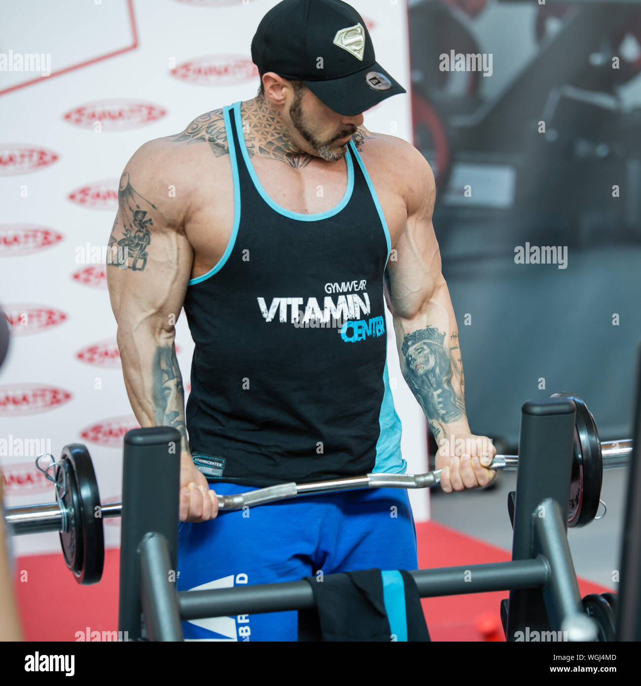 Professional Bodybuilder with Hat doing Weightlifting Exercises at Gym