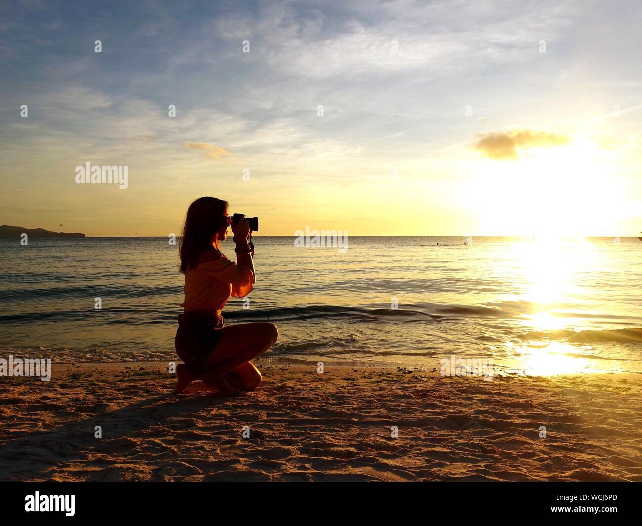 Woman kneeling sand beach sunset beach hi-res stock photography and ...
