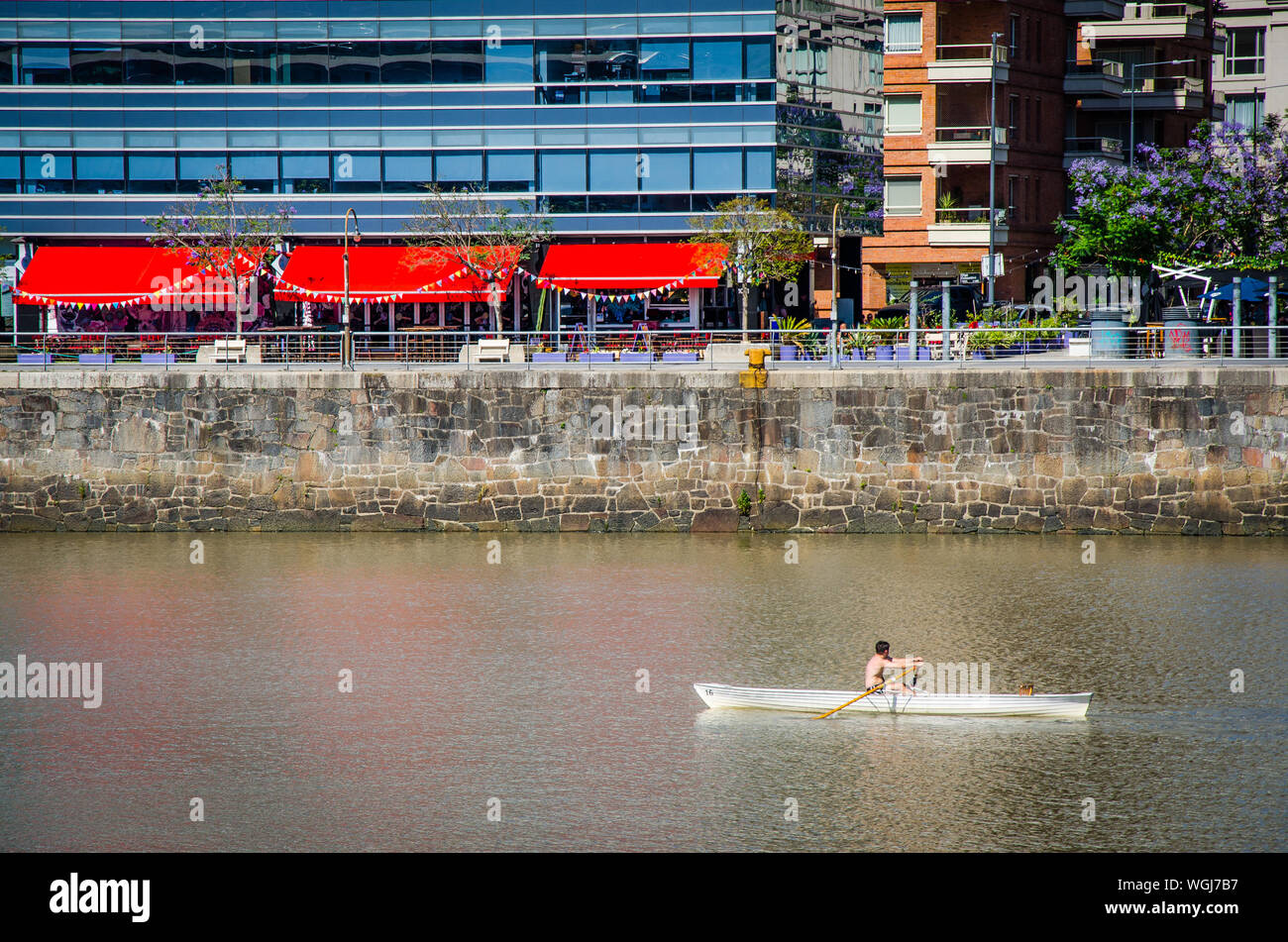 Man Rowing Boat On Lake By Buildings In City Stock Photo