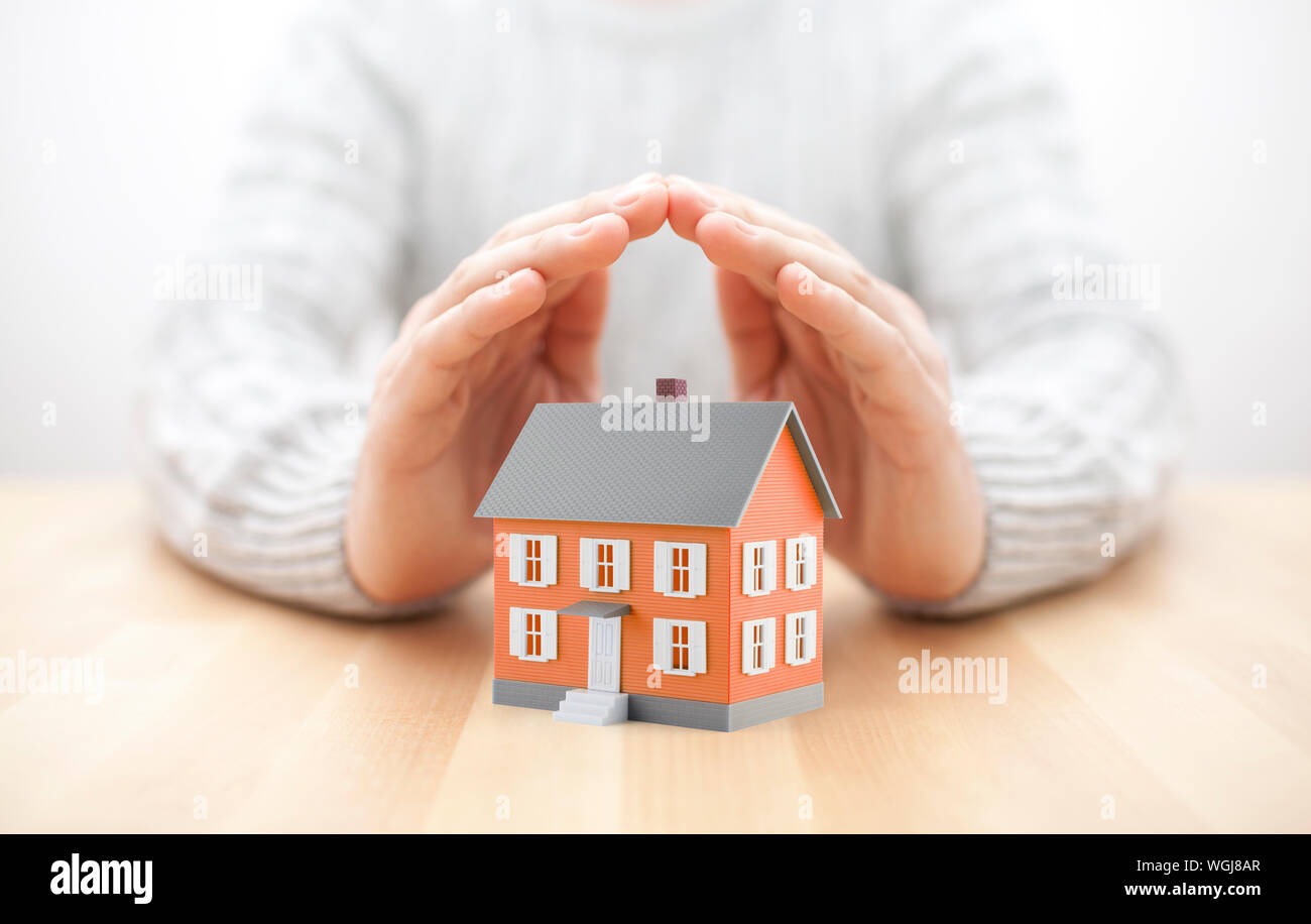 Small orange house covered by hands Stock Photo
