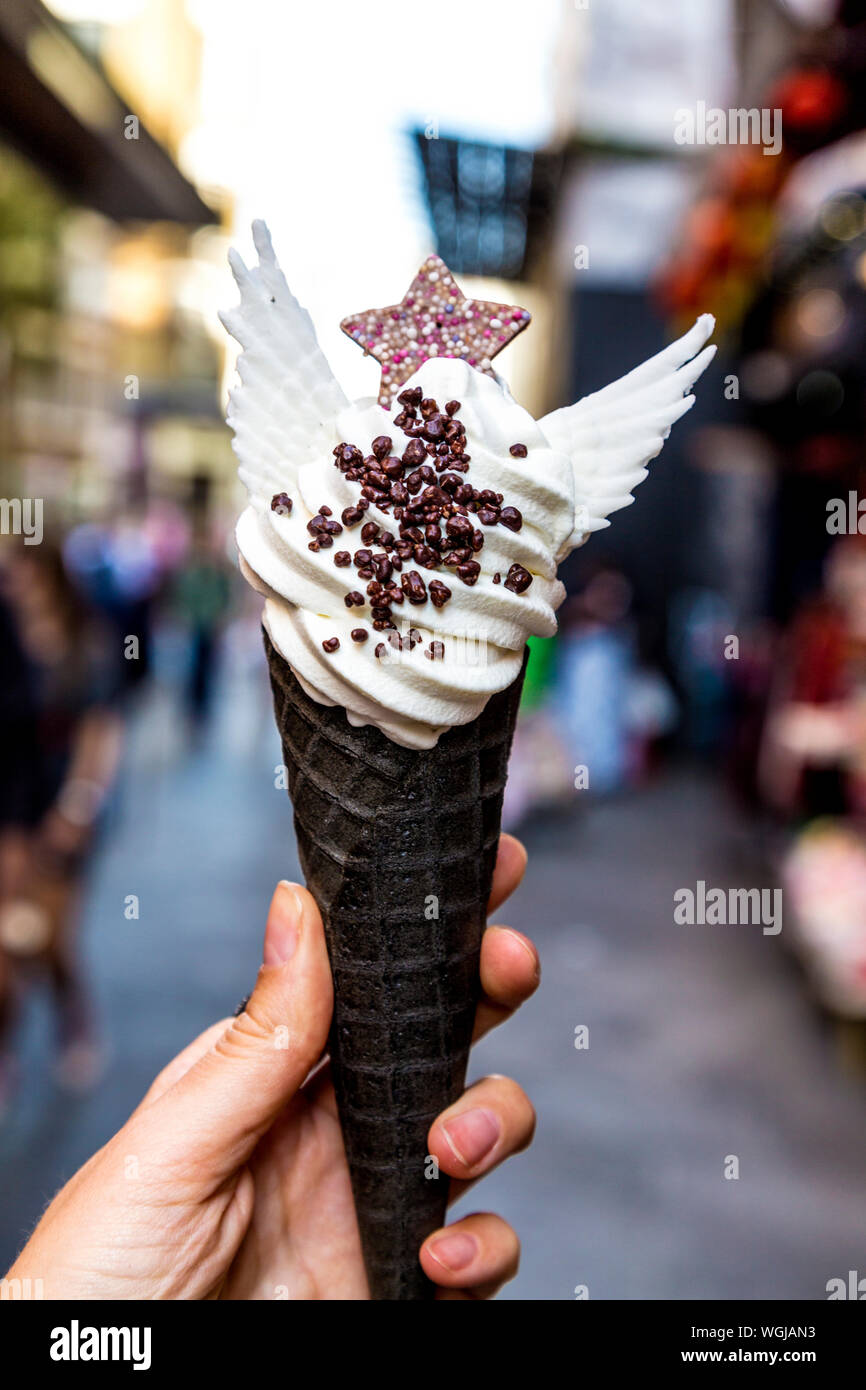 Vanilla soft serve ice cream decorated with wings and star in a black cone at Taiyakiya, Chinatown, London, UK Stock Photo
