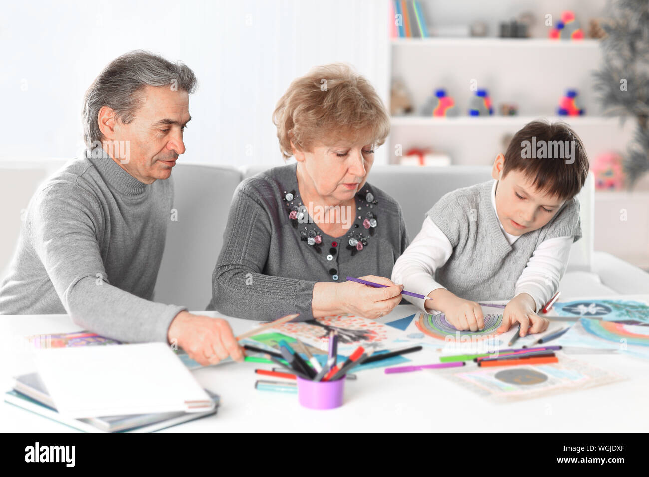 Little boy painting with grandpa and grandma Stock Photo