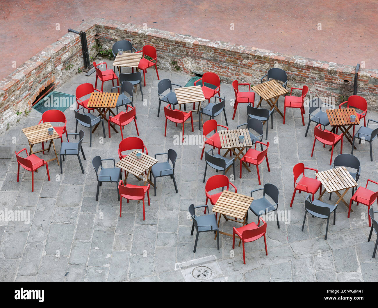 Empty cafe wooden tables and red and black chairs, view from above. Livorno Old Fortress, Italy. Stock Photo