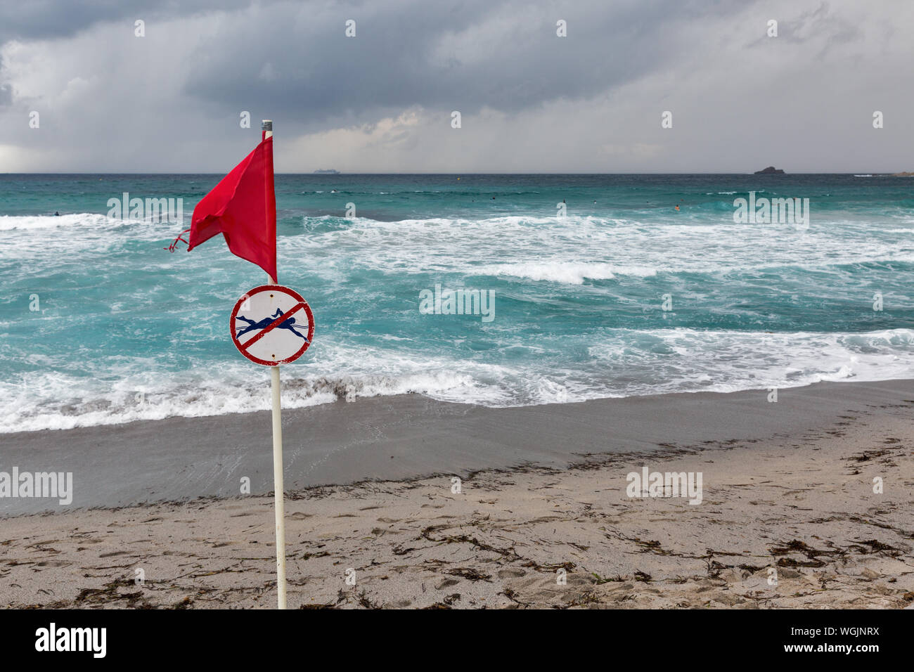Red warning flag with no swimming symbol on sea beach Stock Photo