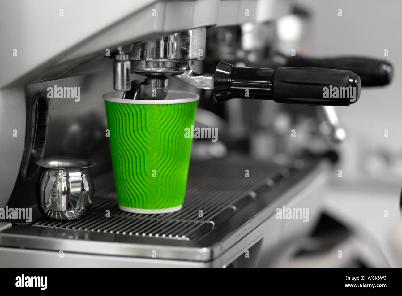 A coffee machine pours a freshly brewed finished drink in a green eco