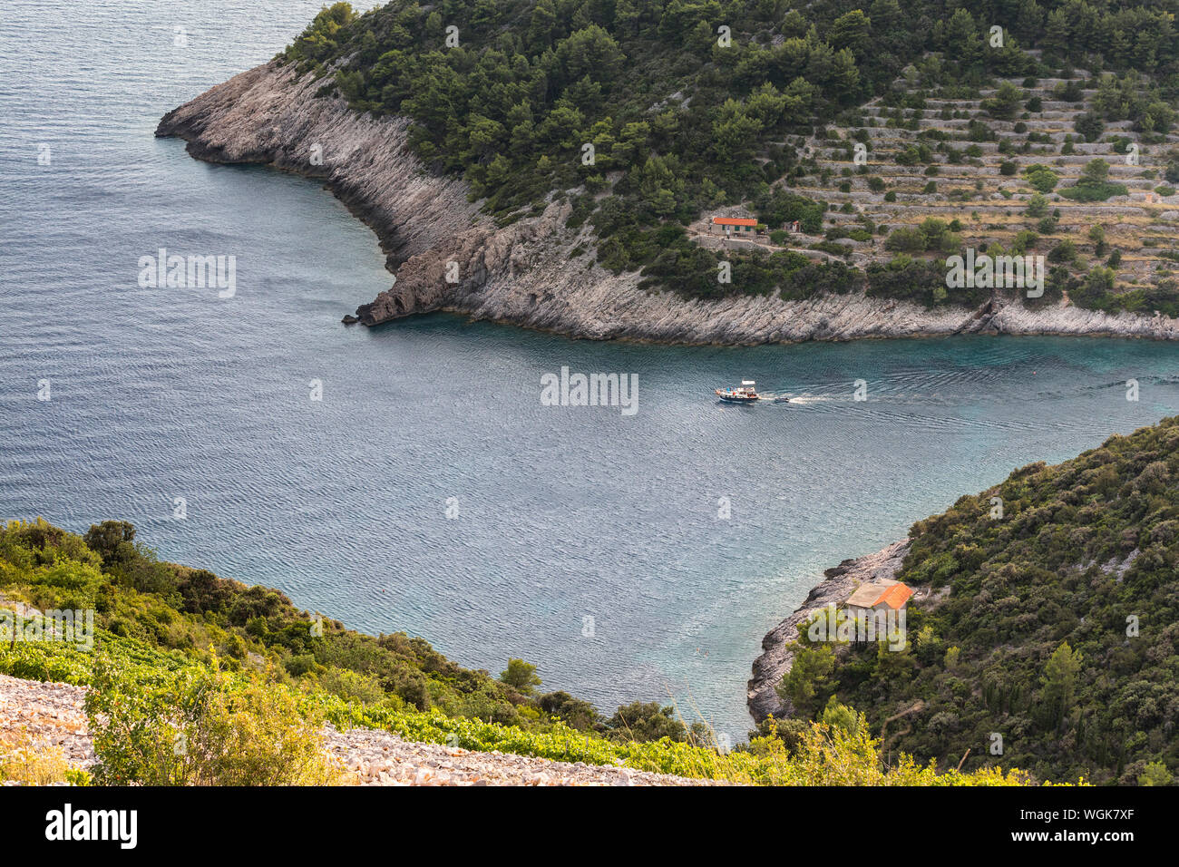 Small boat sails from rocky bay in Korcula island Stock Photo