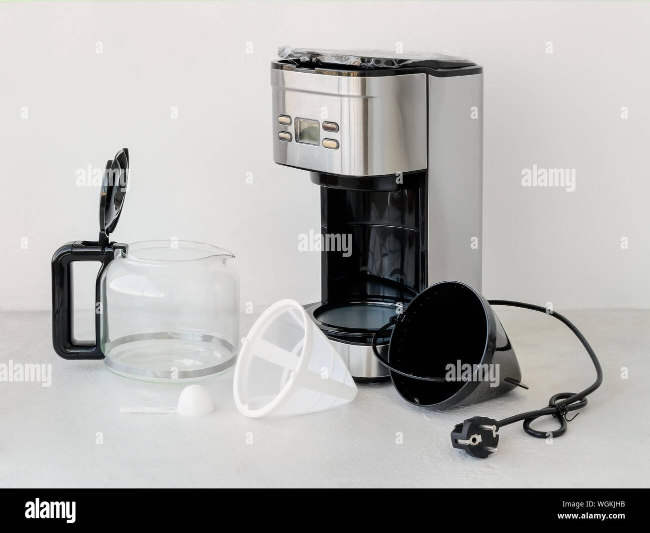 Drip-type coffee maker comprises: coffee machine, glass jug, basket mesh filter, removable filter holder, measuring spoon. Home electrical appliances. Stock Photo