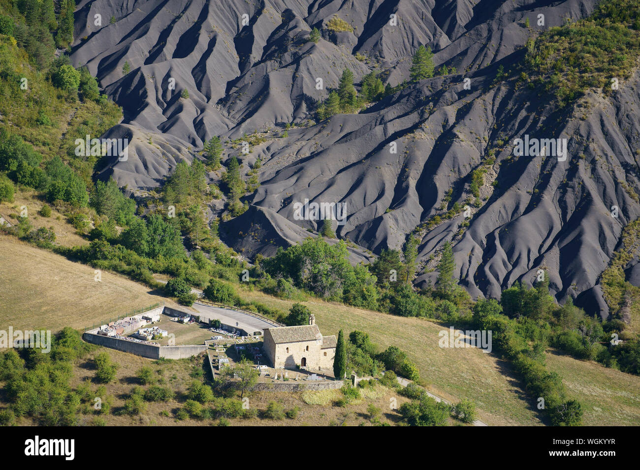 AERIAL VIEW. La Robine-sur-Galabre's 12th century Saint-Pons Chapel with a landscape of badlands (black marl) in the background. France. Stock Photo