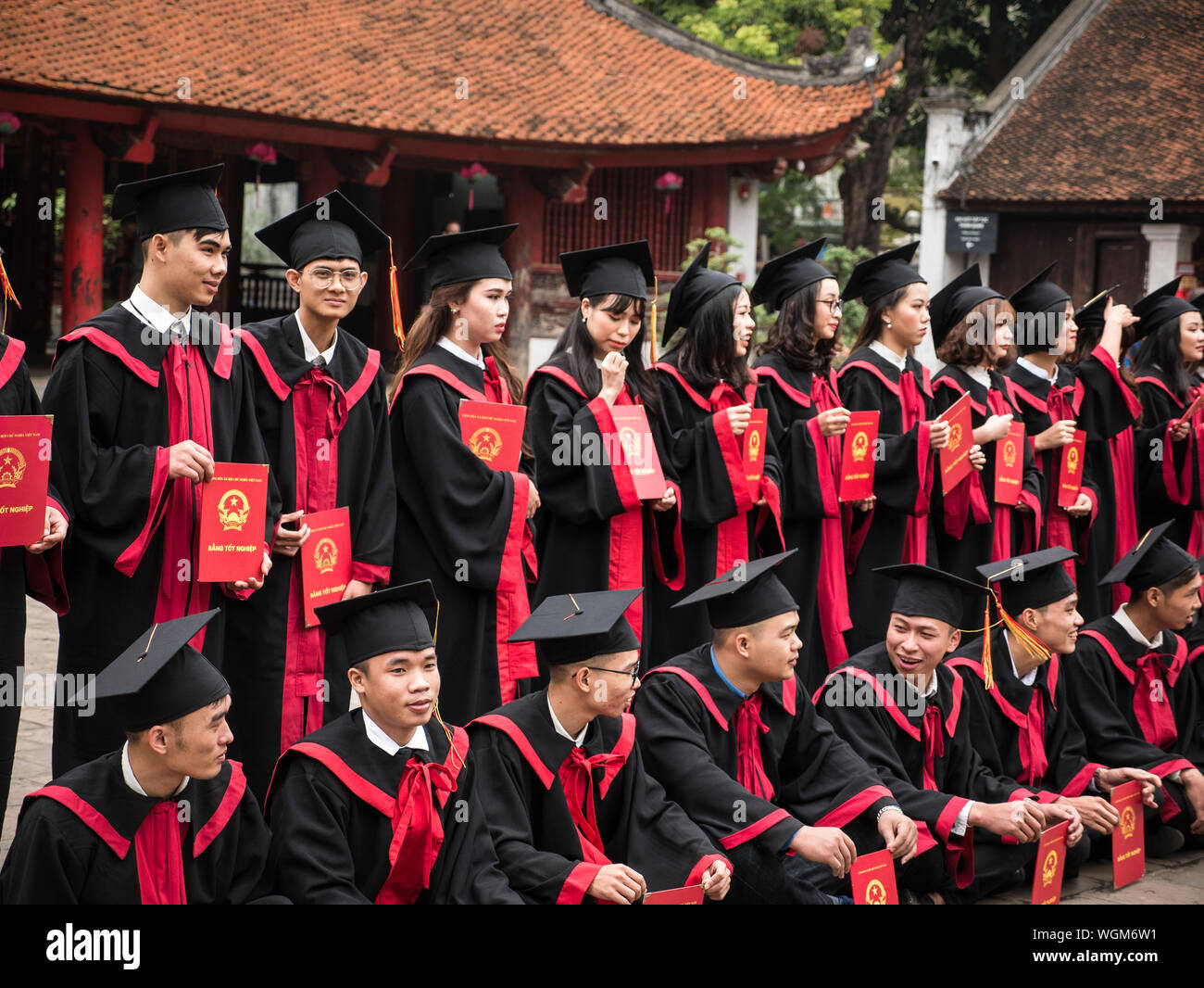 Vietnamese students celebrating university graduation in tradtional costume with certificate and hat at Temple of Literature, Hanoi, Vietnam, oblique Stock Photo